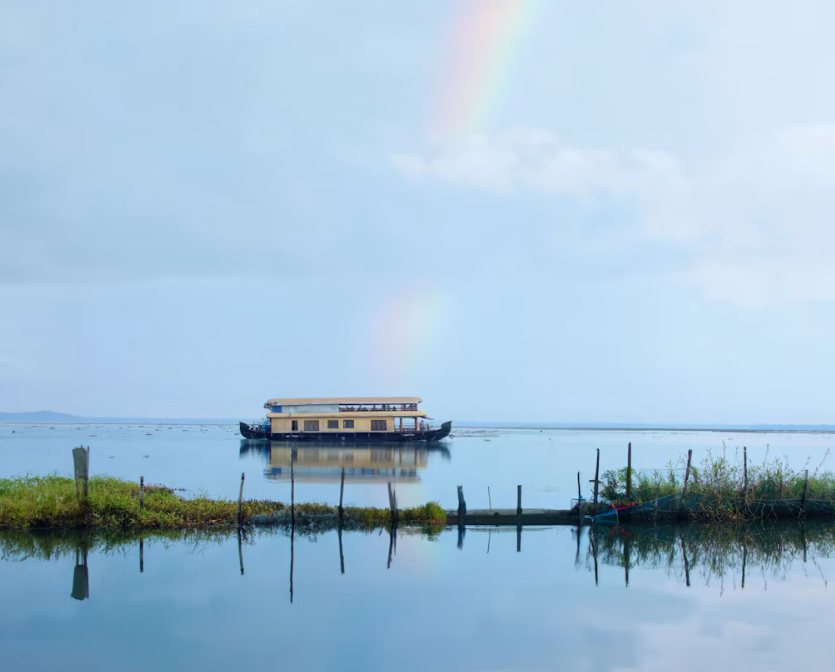 A houseboat on Vembanad Lake under a rainbow